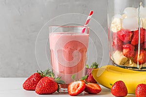 Glass of healthy smoothie or milkshake made of strawberry, banana, almond milk with blender and straw photo