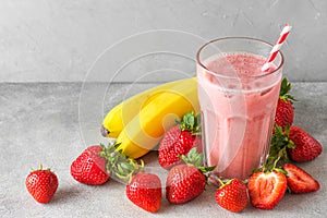 Glass of healthy smoothie or milkshake made of strawberry, banana and almond milk with a straw