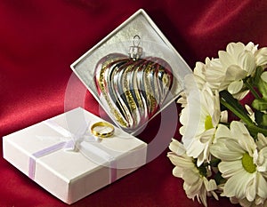 Glass heart in a box with flowers and a golden ring