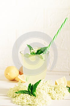 A glass of homemade elderflower lemonade with freshly picked elderflowers. The flowers are edible and can be used to add