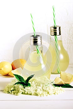 A glass of homemade elderflower lemonade with freshly picked elderflowers. The flowers are edible and can be used to add flavour