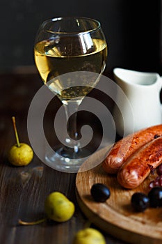 Glass of homemade pear wine with a snack. Grilled sausages, cheese, olives. Menu and restaurant concept.