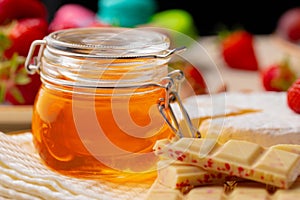 Glass honey jar on background of fruits and sweets