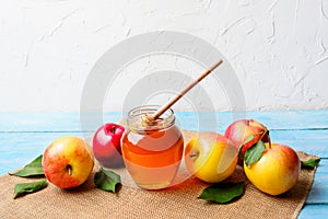 Glass honey jar with dipper and apples copy space