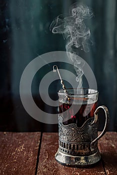 A glass of hot black tea in a vintage cup holder. Wonderful still life. Selective focus. The glass is opposite the window