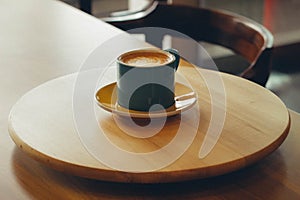 A glass of hot cappuccino on a wooden table in the morning