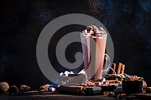Glass of hot chocolate cocoa drink sprinkled with cocoa powder. Dark background. Winter food and drink concept with Copy space