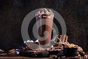 Glass of hot chocolate cocoa drink sprinkled with cocoa powder. Dark background. Winter food and drink concept with Copy space