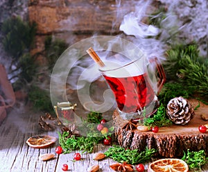 Glass of hot mulled wine for the new year with ingredients for cooking, nuts and Christmas decorations