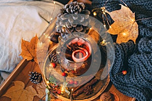 Glass of hot steaming tea and autumn plants on wooden table