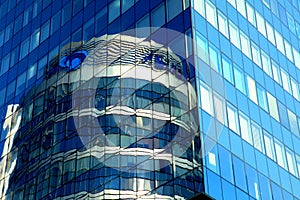 Glass house, high-rise office building, modern skyscraper in which round glass tower is reflected. Tall blue apartment building