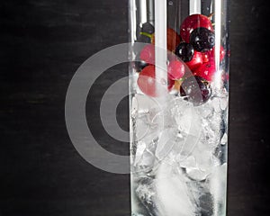 Glass of ice with berry gooseberries red black currants and water. Refreshing cocktail. Summer drink.