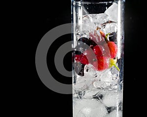 Glass of ice with berry gooseberries red black currants and water. Refreshing cocktail. Summer drink.