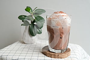 A glass of ice chocolate latte on wood plate