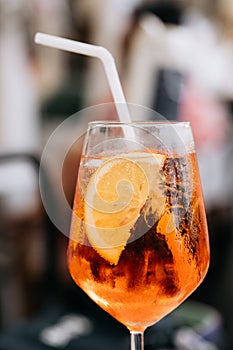 Glass of ice cold Aperol spritz cocktail served in a wine glass, decorated with slices of orange. Aperitive in street