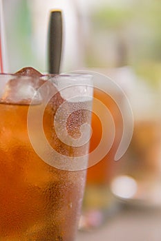 a glass of ice tea with straw and spoon with bubbles