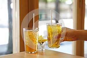 Glass of iced bael fruit herbal drink and Chinese chrysanthemum tea with ice on wooden table.