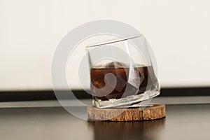 A glass of iced black coffee on wood plate