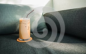 Glass of iced coffee on the grey color sofa