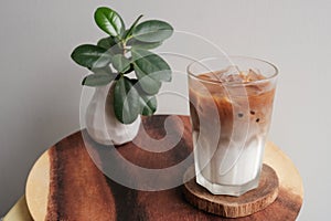 A glass of iced coffee latte on wood plate