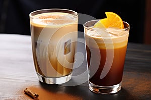 a glass of iced drink with lemon next to a hot latte with cinnamon