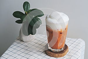 A glass of iced milk tea on wood plate