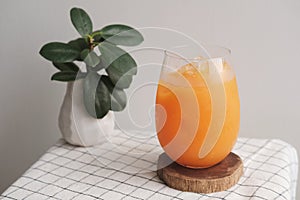 A glass of iced Orange juice on wood plate