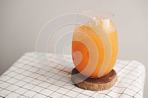 A glass of iced Orange juice on wood plate