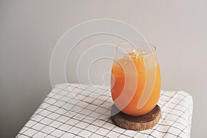 A glass of iced Orange juice on wood plate