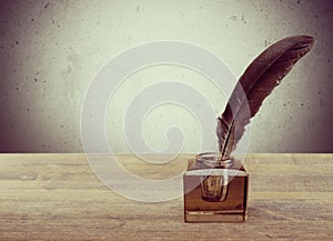 Feather quill pen and glass inkwell on library