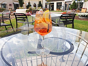 A glass of Italian cocktail Spritz stands on a glass table on the terrace