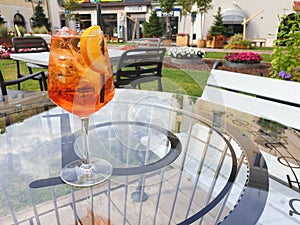 A glass of Italian cocktail Spritz stands on a glass table on the terrace