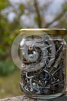 Metalware storage inside jar with golden metal lid. Industrial objects closeup photo