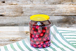 Glass jar with canned cherries fruits. Preserved fruits concept, canned fruits compote isolated in a rustic composition