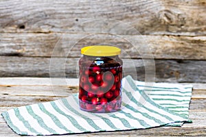 Glass jar with canned cherries fruits. Preserved fruits concept, canned fruits compote isolated in a rustic composition
