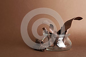 Glass jar with chocolate bars and curls on color background.