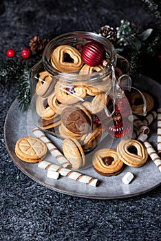 Glass jar with Christmas Linzer cookies on caramic rustic plate