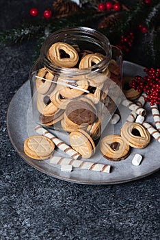 Glass jar with Christmas Linzer cookies on caramic rustic plate