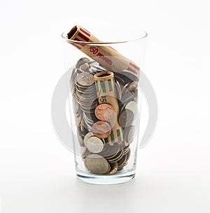 Glass jar of coins in cup on countertop desk money savings debt bank rich poor dollar finance wealth change market cash