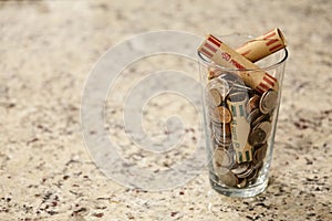 Glass jar of coins in cup on countertop desk money savings debt bank rich poor dollar finance wealth change market cash