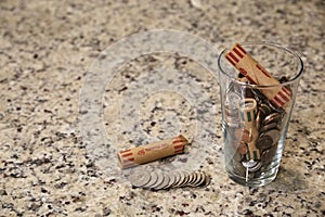 Glass jar of coins in cup on countertop desk money savings debt bank rich poor dollar finance wealth change market cash