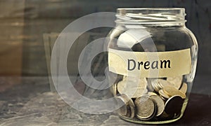 Glass jar with coins and the inscription `Dream`. Family budget and finances. Distribution of cash savings. Fulfilling a cherished photo