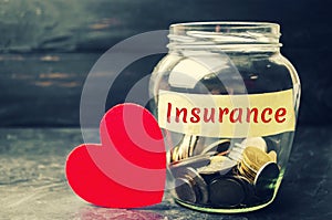 Glass jar with coins and the inscription `Insurance`. The concept of medical insurance of life, family, health. Healthcare. Red he