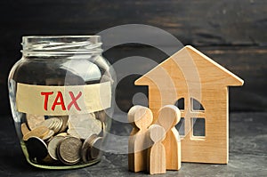 Glass jar with coins and the inscription `tax` and a small house. Taxes on real estate, payment. Penalty, arrears. Register of tax