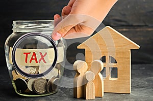 Glass jar with coins and the inscription `tax` and a small house. Taxes on real estate, payment. Penalty, arrears. Register of tax