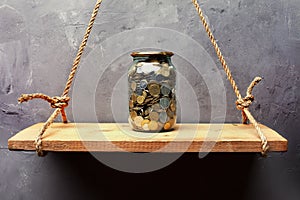 Glass jar with coins on the old wood shelf