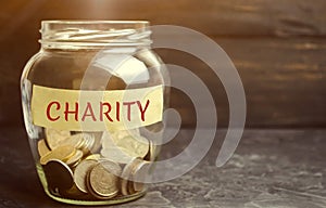 Glass jar with coins and the word Charity. The concept of accumulating money for donations. Saving. Social medical help from volun