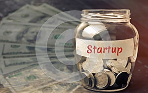 Glass jar with coins and the word ` Startup `. The concept of raising funds for a startup. Charitable contributions to translate i