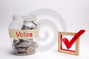 Glass jar with coins and the words Votes and a checkbox. Concept of voting for money. Bribing voters. Corruption in the electoral photo