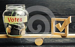 Glass jar with coins and the words `Votes` and a checkbox on the scales. Concept of voting for money. Bribing voters. Corruption i photo